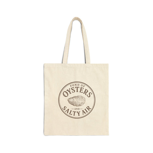 A natural canvas tote bag with two shoulder straps, featuring a circular brown graphic print on the front that reads 'FOND OF OYSTERS AND SALTY AIR' around an oyster illustration, shown against a plain white background.