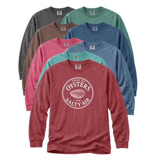 Six long-sleeve crewneck t-shirts in different colors are arranged in a fan shape on a white background. The front shirt is a heathered dusty rose red with a white circular graphic that reads 'FOND OF OYSTERS AND SALTY AIR' with an oyster illustration.