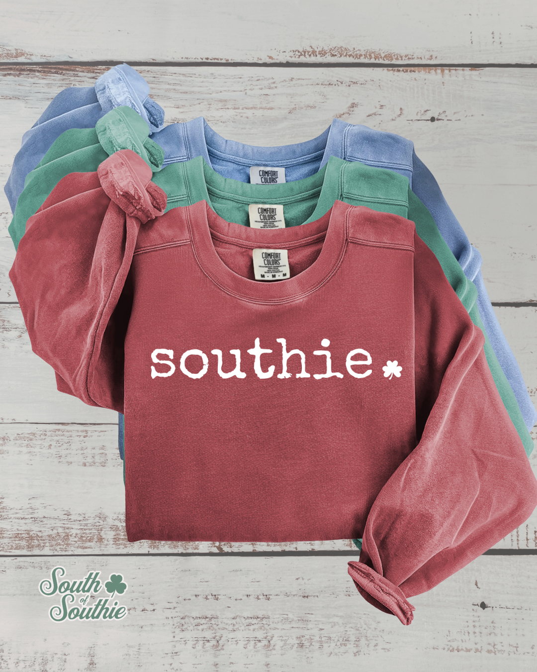 Stack of colorful sweatshirts with 'southie' branding on a wooden surface.