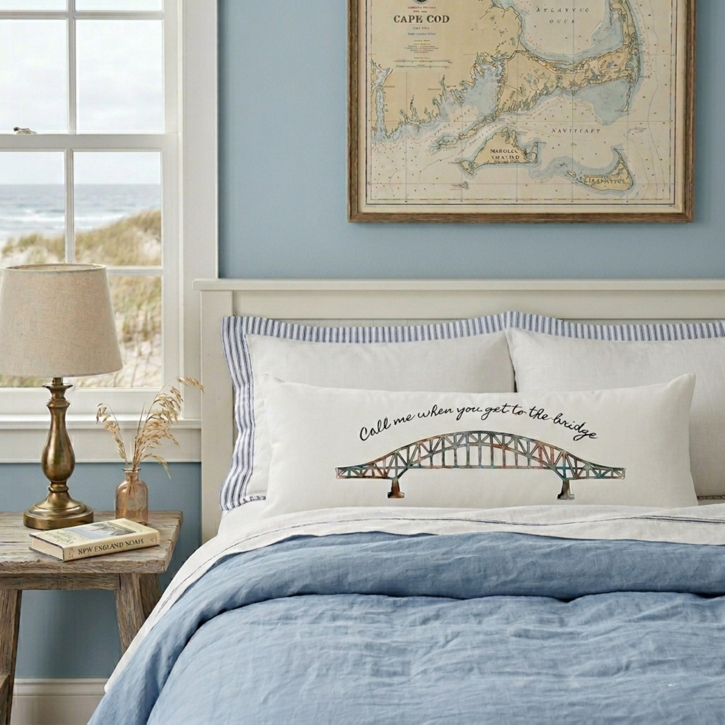 white body pillow on a bed in a cape cod beach house with a watercolor design of the sagamore bridge and the words call me when you get to the bridge. 